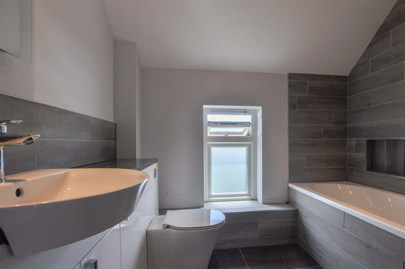 Modern premium bathroom with white walls, white bathroom suite and grey slate tiles.