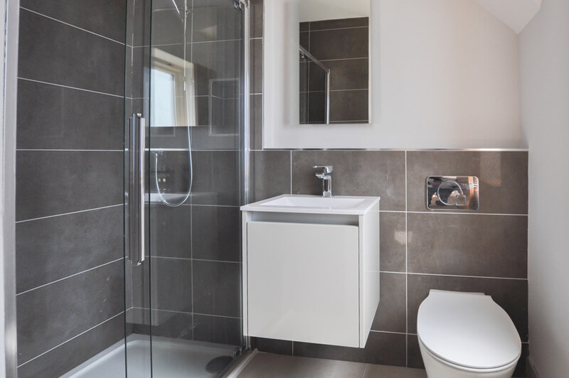 Modern premium bathroom with white walls, white bathroom suite, shower and grey slate tiles.