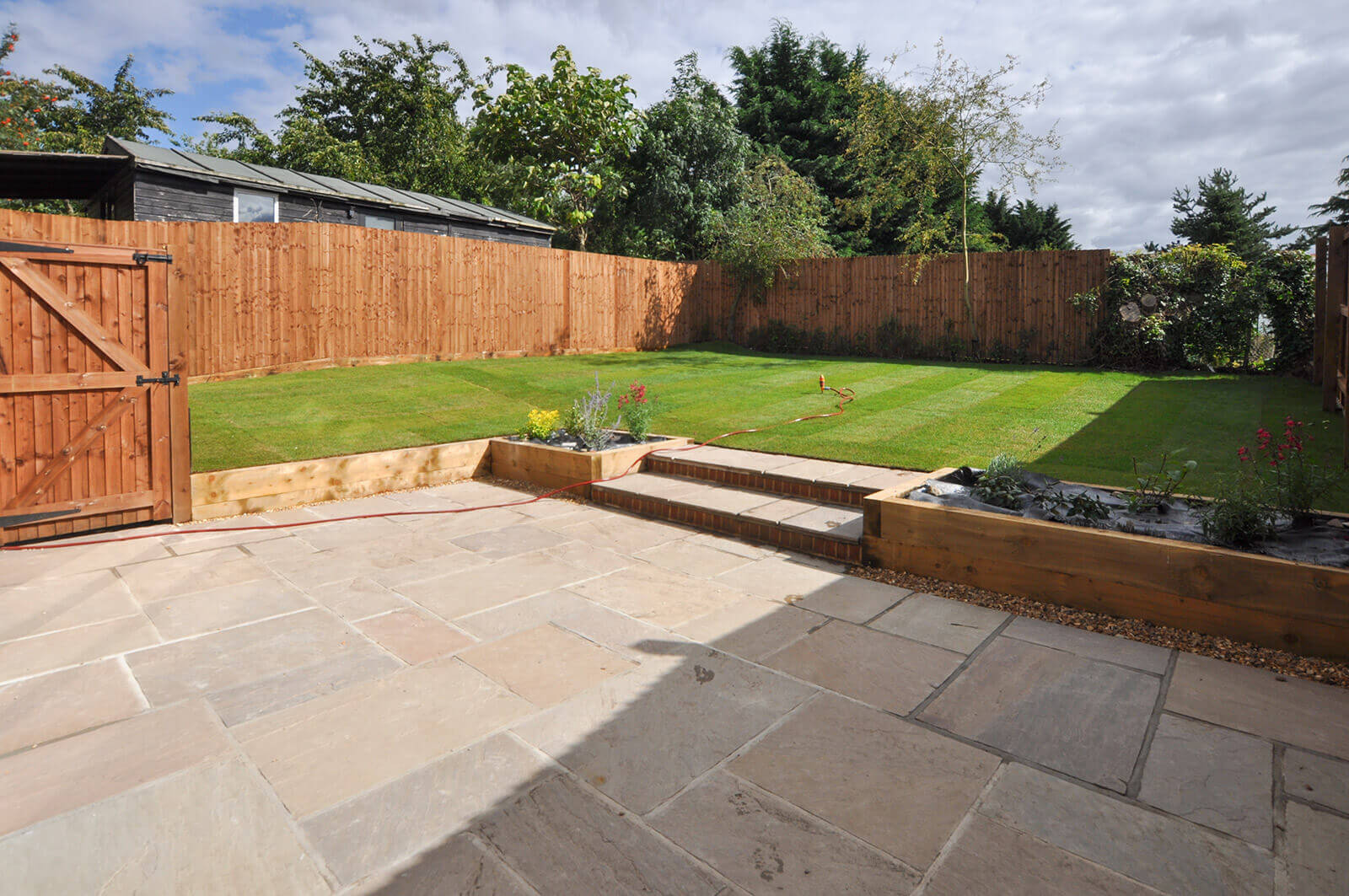 View of patio leading to a slightly raised garden accessed by a couple of steps.