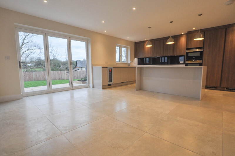 Spacious open plan living room and premium kitchen with large tiled flooring and glass doors to the back garden.