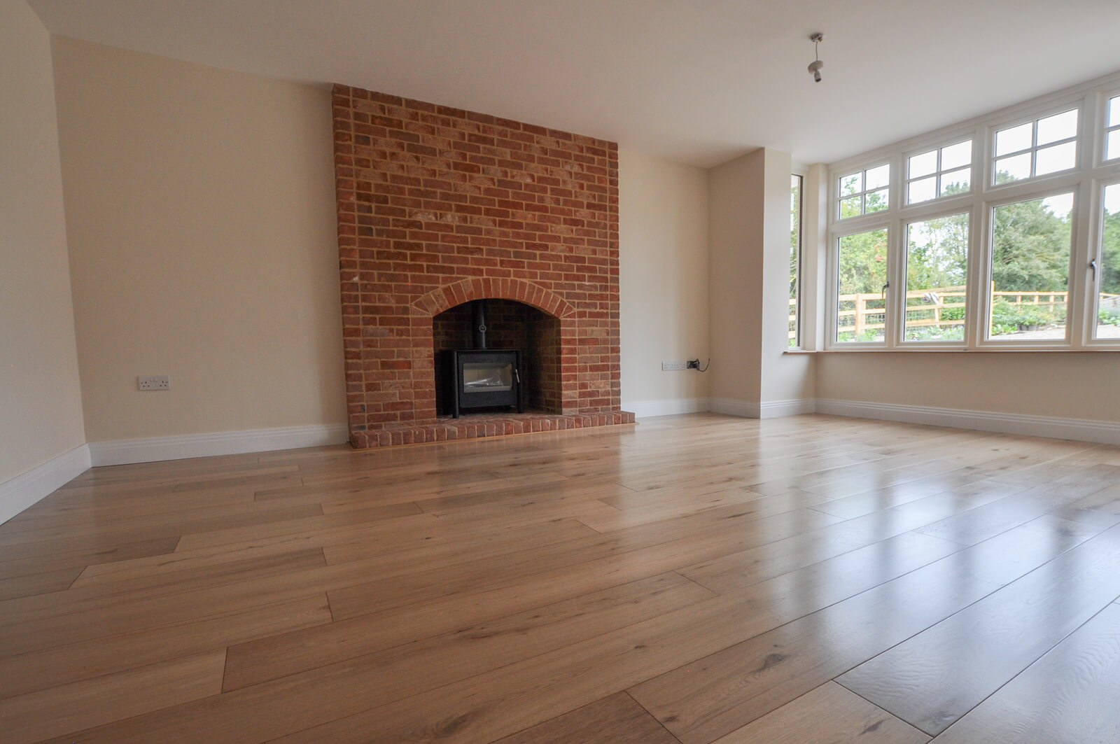 Living room with hard wood floor and large brick fire place.