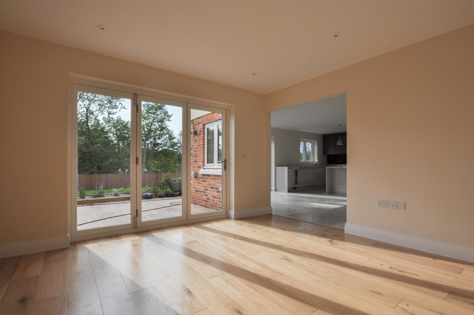 Living area with glass doors to the side patio and a passage way through to the open plan kitchen.