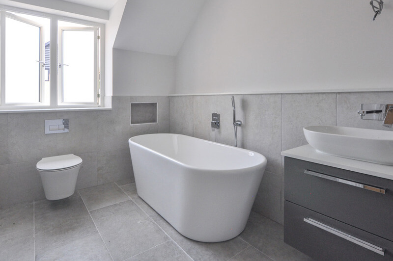 Premium bathroom with white suite and large grey tiles.