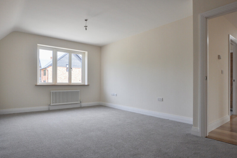 Large bedroom with grey carpet and white walls.