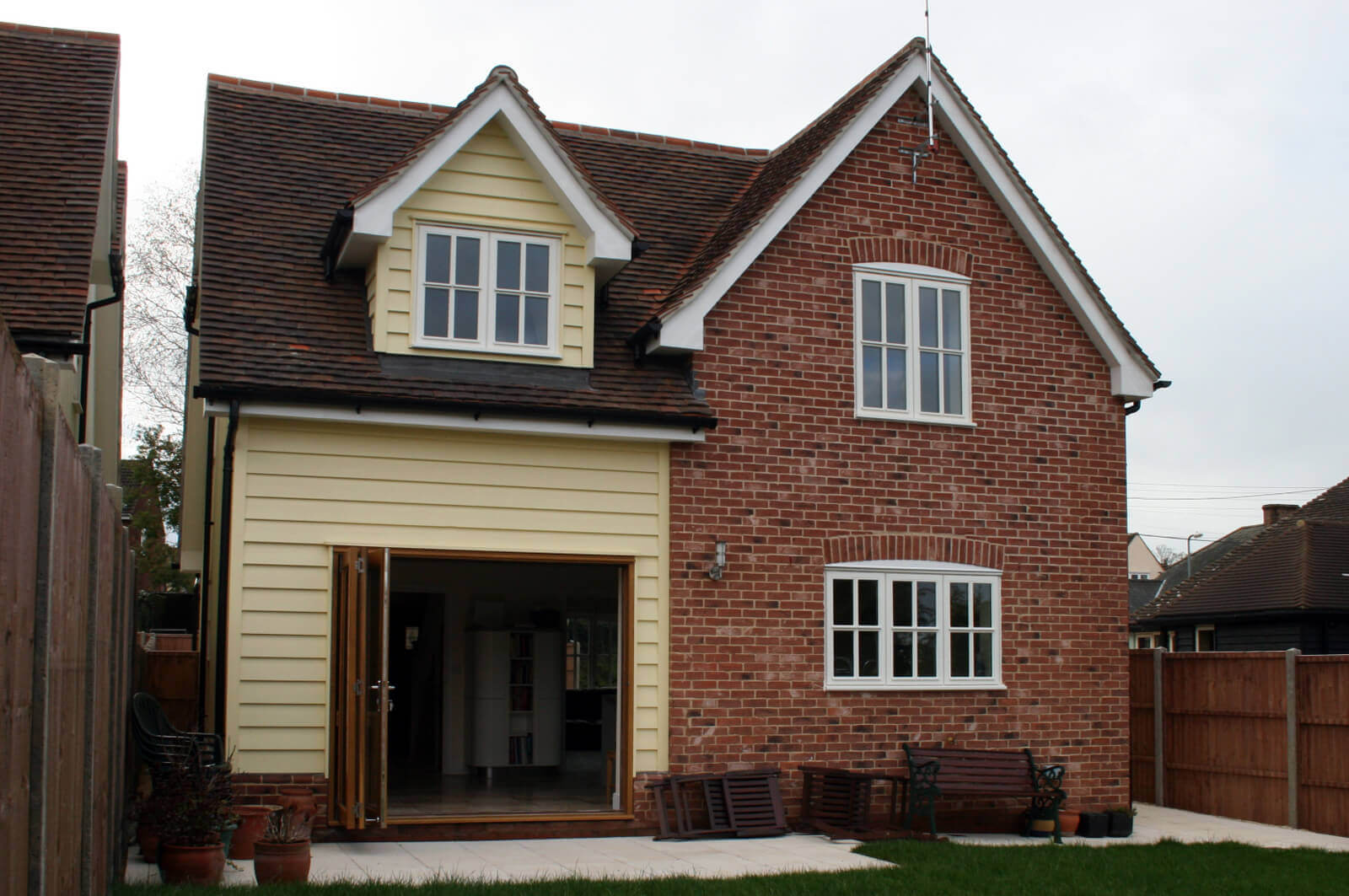 Rear view of detached house with open bi-fold doors leading into garden.