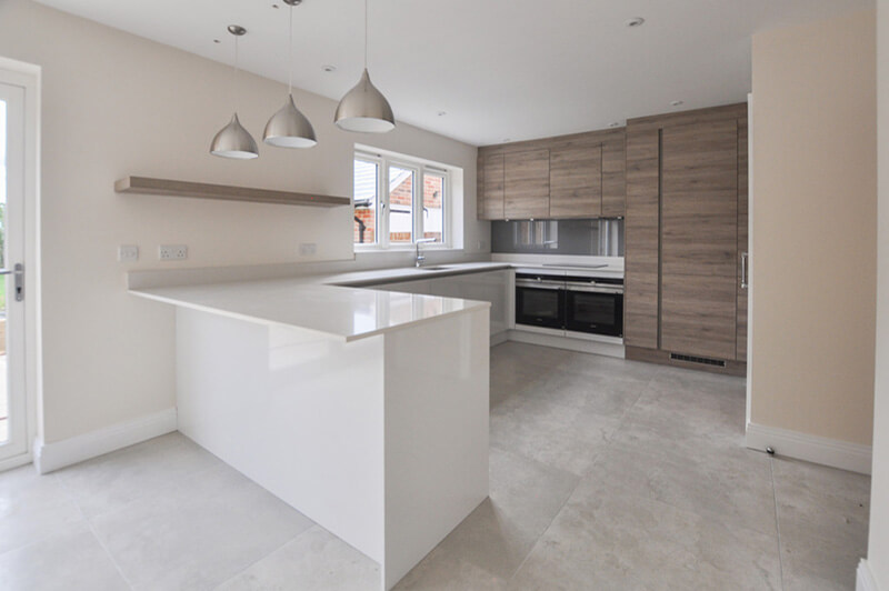 Open plan white and wooden kitchen with L-shaped worktop.