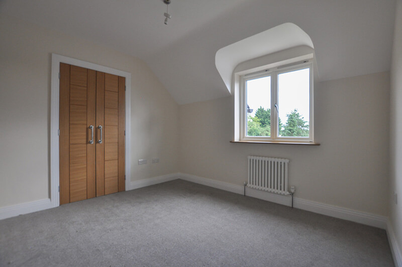 Top floor bedroom with white walls, in-built wardrobe and grey carpet.