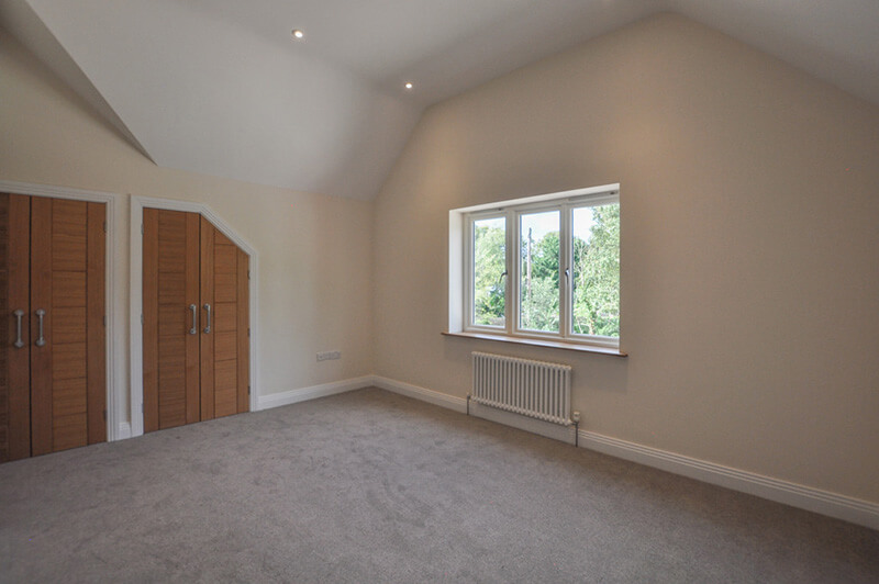 Spacious bedroom with white walls, two in-built wardrobes and grey carpet.