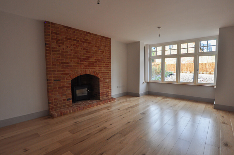 Living room with large brick fireplace and large window.