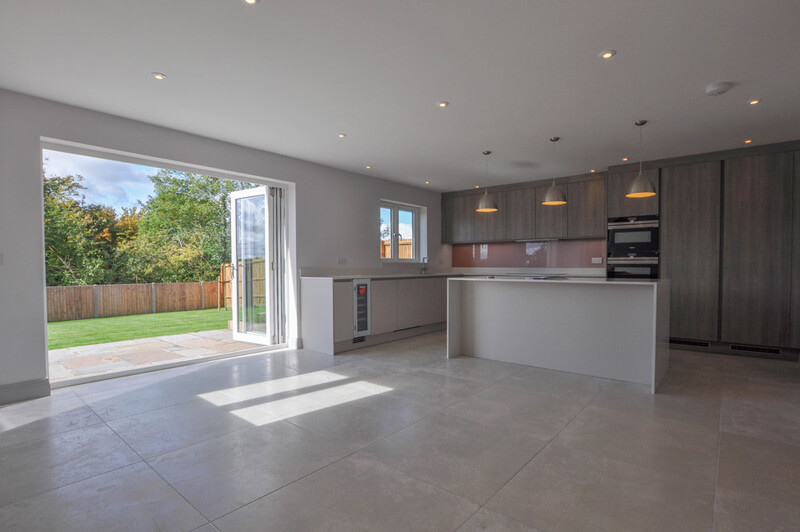 Large open plan kitchen diner with open bi-fold doors leading onto garden.