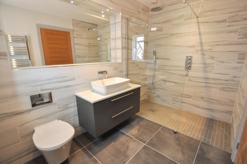 Large premium bathroom with white and grey suite, shower and tiled floor and walls.