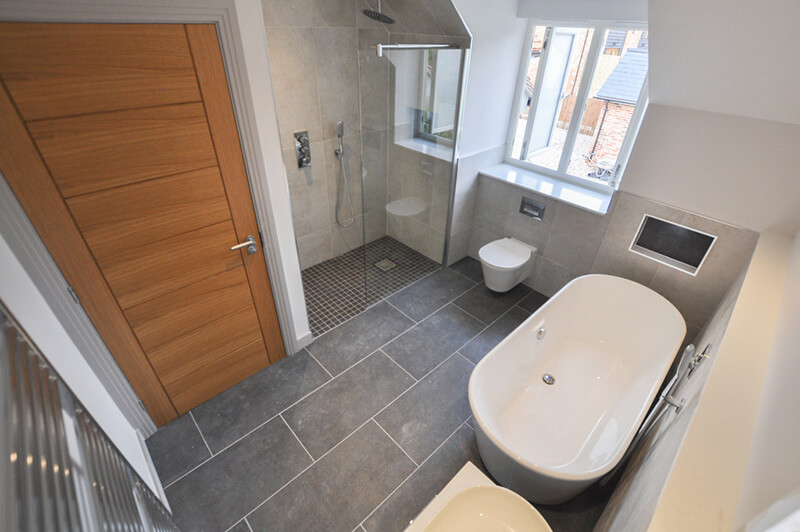 Bathroom with white suite, tiled floors, shower and bath.